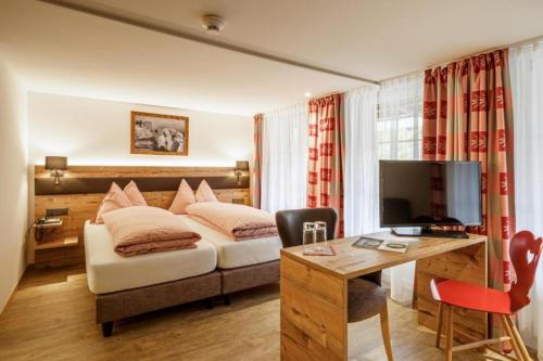 维尔德斯韦尔Alpenblick Hotel & Restaurant Wilderswil by Interlaken的配有一张床和一张书桌的酒店客房