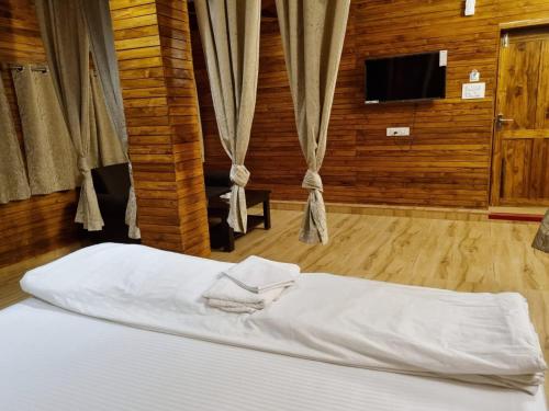 JaypurWoods Residency的一间卧室配有一张带白色床单的床和电视。