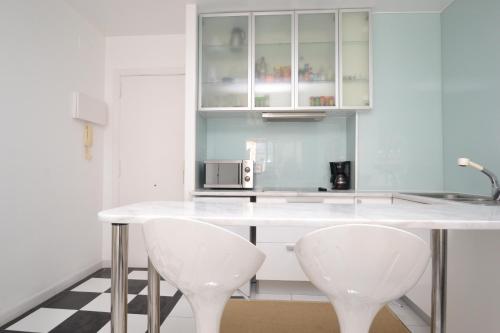 锡切斯Viva Sitges - Mayo Terrace的厨房配有白色的柜台和2把白色的椅子
