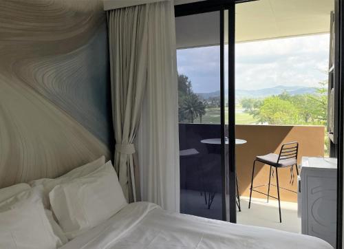 邦涛海滩Brand new Condo in Laguna near golf course的一间卧室配有一张床,阳台配有桌子