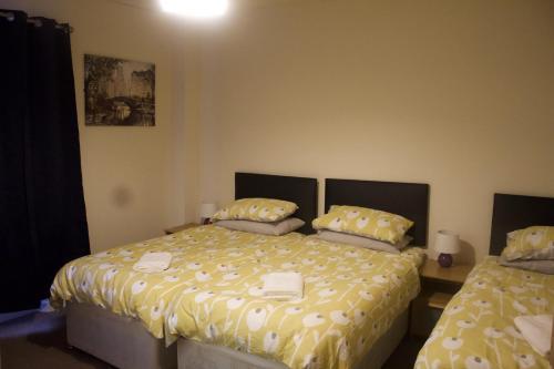 滨海韦斯顿Elm Tree Guest House的一间卧室配有两张带黄色棉被的床