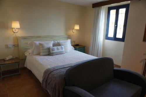 帕拉莫斯Hotel Sant Joan的一间卧室配有一张带椅子的床和一扇窗户