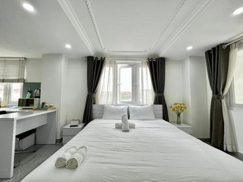 胡志明市MơMơ Residence的卧室配有一张带拖鞋的大型白色床。