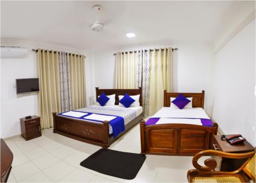 卡图纳耶克Ronaka Airport Transit Hotel的一间卧室配有两张床、一张桌子和一台电视。