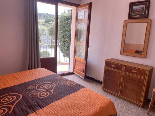滨海托萨艾尔索尔公寓的一间卧室配有一张床、镜子和窗户