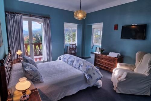 拉库布蕾Gran Hotel La Cumbre的一间带蓝色墙壁、一张床和电视的卧室