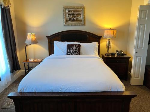 布兰森Historic Branson Hotel - Heritage Room with Queen Bed - Downtown - FREE TICKETS INCLUDED的一间卧室配有一张带两盏灯的大型白色床。