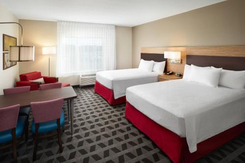 利斯堡TownePlace Suites by Marriott Leesburg的酒店客房带两张床和一张桌子以及椅子。