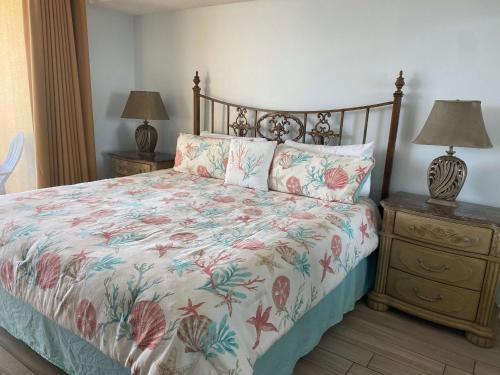 奥兰治比奇Summer House 703B by ALBVR - Great Beachfront Condo with Oversized Balcony & Amazing Views!的一间卧室配有一张带花卉床罩和2个床头柜的床。