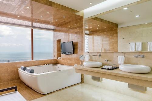 巴拿马城巴拿马喜来登大酒店的一间带两个盥洗盆和浴缸的浴室以及一台电视。