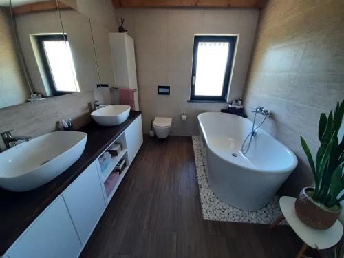 House Na Starom Kućištu的一间带两个盥洗盆、浴缸和卫生间的浴室
