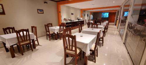 圣胡安Ensenada Hotel的一间设有白色桌椅的餐厅和一间酒吧