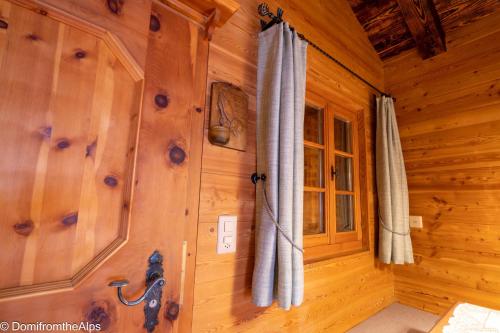 萨斯阿尔马格尔豪泽尔特拉初度假屋的小屋内带木墙和窗帘的房间