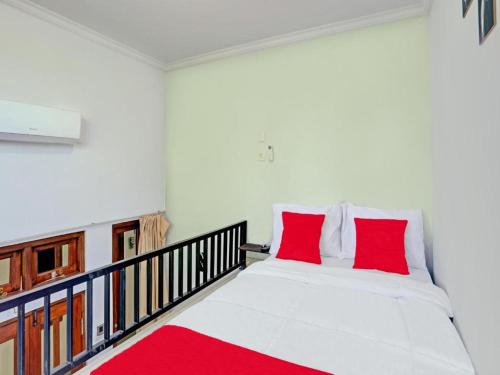 吉安雅Tiny House Gianyar的卧室配有带红色枕头的白色床