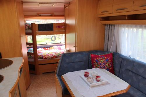 阿赫特克克Caravan 't Koekoeksnest的客厅配有桌子、沙发和双层床。