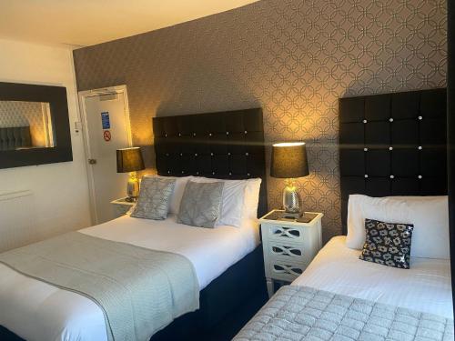 绍斯波特Aaron的酒店客房设有两张床和床头柜。