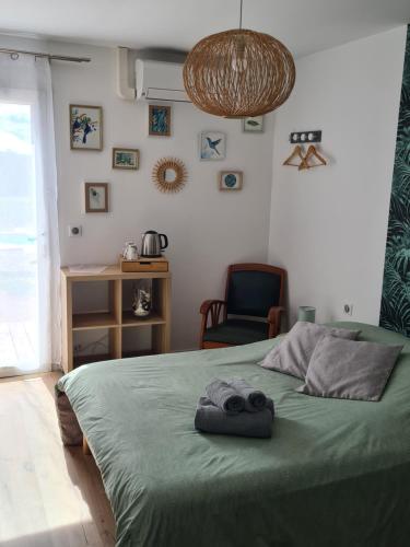 Orgnac-lʼAvenLe Petit Chêne的一间卧室配有一张带椅子的绿色床