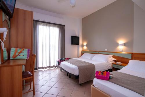 里米尼Hotel Holland的酒店客房配有两张床和一张书桌