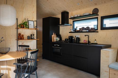 宁斯佩特Vague Luxurious Tiny House Luxe Wellness, Spa Bad,Beamer, Veluwe的厨房配有黑色橱柜、桌子和柜台。