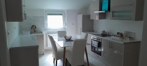 布尔奇科Apartman XXL的厨房配有白色橱柜和桌椅