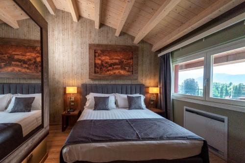皮索涅Lake Hotel La Pieve的一间卧室设有两张床和两个窗户。