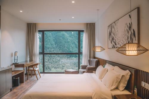 张家界Zhangjiajie National Park Nvue Resorts的酒店客房设有一张大床和一张书桌。