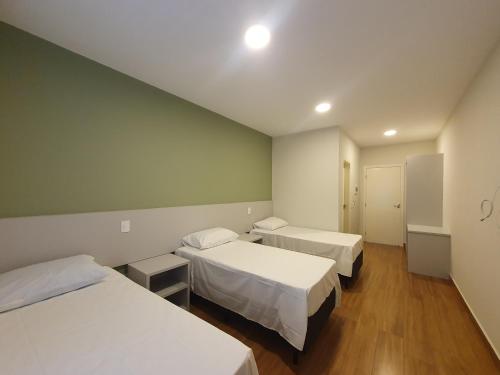 阿瓜斯迪林多亚Pousada Thermas das Montanhas的一间医院房间,配有两张床,一间房间配有两张桌子