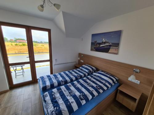 尤斯托尼莫斯基Domki luksusowe Kapitan的一间卧室配有一张带蓝色棉被的床和窗户。