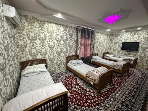 Yukary-UkhumHayat Guesthouse Nuratau Mountains的一间设有三张床的客房,墙上设有一台电视。