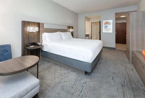 达拉斯Holiday Inn Express & Suites - Dallas Park Central Northeast, an IHG Hotel的配有一张床和一把椅子的酒店客房