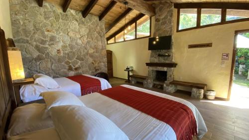萨卡特兰Cabañas La Cascada的一间卧室设有两张床和石墙