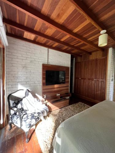 贡萨尔维斯Chalés Vila Flor的一间卧室配有一张床、一台电视和一把椅子