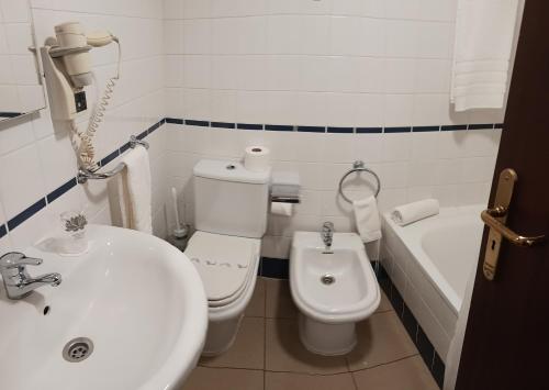 蓬塔德尔加达Hotel Insular的浴室配有盥洗盆、卫生间和浴缸。
