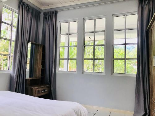 古打毛律Grace Guesthouse的一间卧室设有四扇窗户和一张白色的床