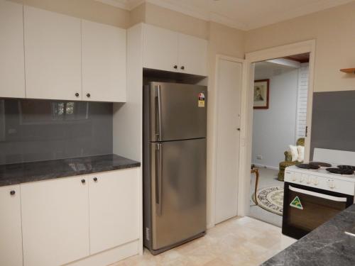 ScoresbyMillie’s cottage的厨房配有不锈钢冰箱和白色橱柜