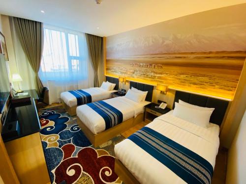 Mazaalai Hotel的酒店客房设有两张床,墙上挂有绘画作品