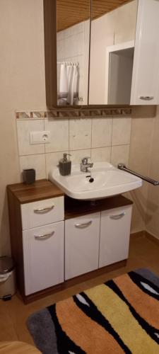 Haus Waldblick的浴室设有水槽、镜子和地毯。