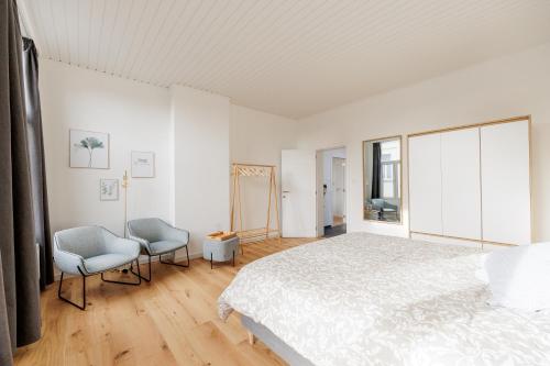安特卫普SurPRIMO - Gerenoveerd appartement的一间白色卧室,配有一张床和两把椅子