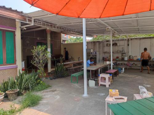 万象Vernice Backpacker Hostel的庭院配有橙色遮阳伞和桌椅。