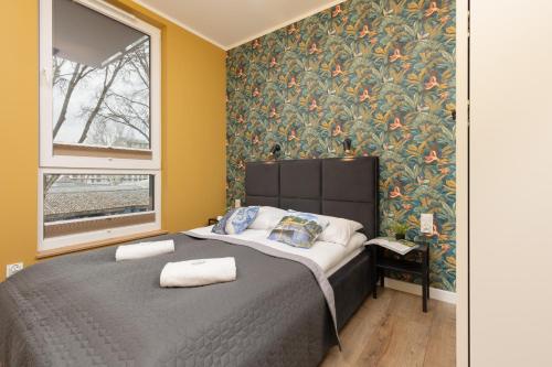 华沙Active City Apartments Warsaw by Renters的一间卧室配有一张带花卉壁纸的床