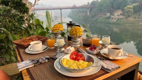琅勃拉邦占城河景月光酒店的一张桌子,上面有水果和咖啡,还有一条河流