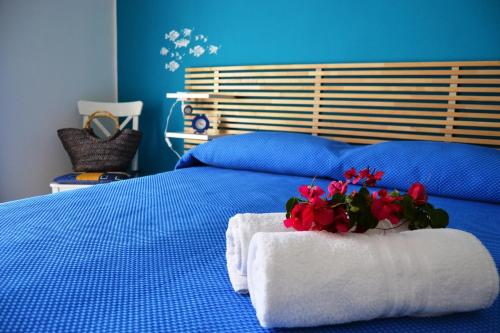 圣维托罗卡波B&B Vivere il Mare的一张蓝色的床,上面有毛巾和鲜花