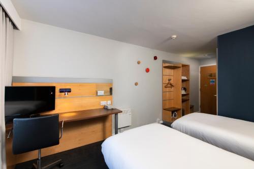 汉密尔顿汉密尔顿智选假日酒店的一间卧室配有两张床和一张书桌及电视