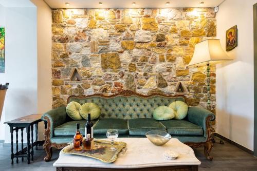 雅典Queen's stone legend, royal living by Acropolis的客厅设有绿色沙发和石墙