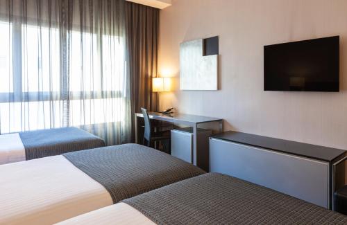 塞维利亚Porcel Torneo的酒店客房设有两张床、一张桌子和一台电视。