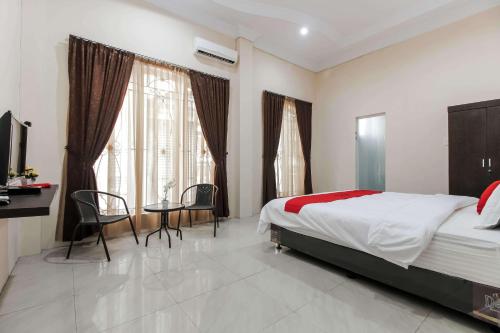 棉兰RedDoorz At Ralica Grand Palladium Medan的卧室配有一张床和一张桌子及椅子