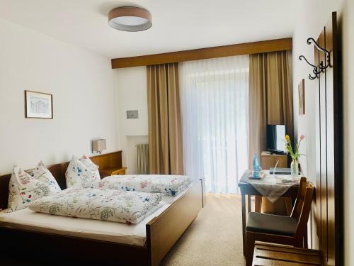 CainesTannerhof Bed & Breakfast的一间卧室配有一张床、一张桌子和一个窗户。