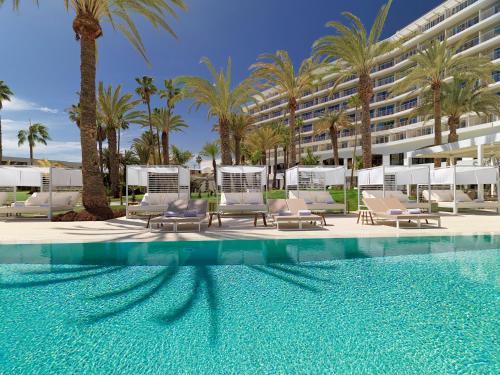 圣阿古斯丁Paradisus by Meliá Gran Canaria - All Inclusive的一座带椅子和棕榈树的游泳池以及一座建筑