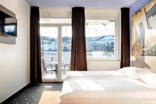 基尔B&B Hotel Kiel-Holstenbrücke的一间卧室设有一张床和一个大窗户