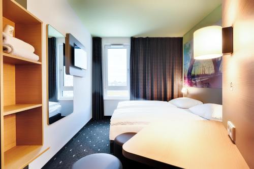 莱茵河畔凯尔B&B Hotel Kehl的酒店客房设有两张床和一张桌子。